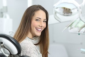 a women sits in a dental chair after dental implant surgery recovery
